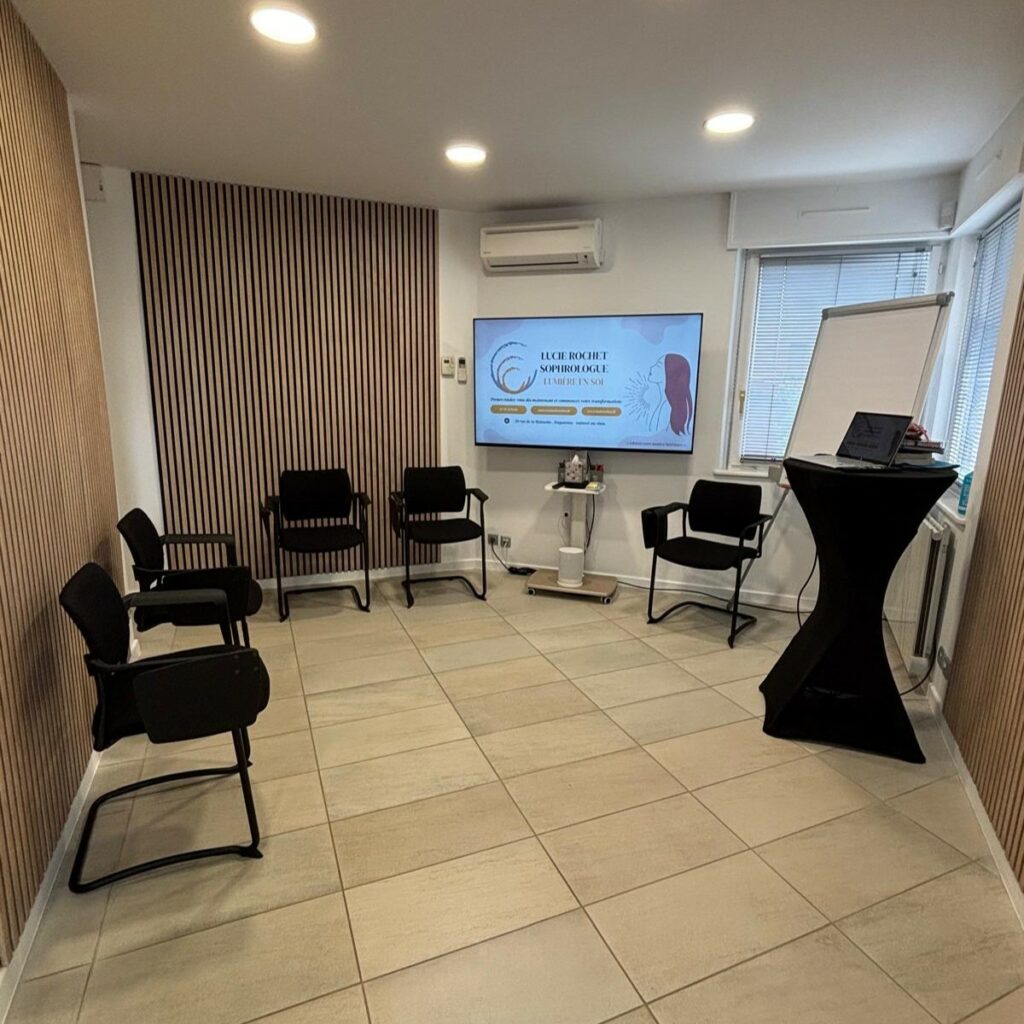 Photo du coin discussion en groupe dans le cabinet, avec des chaises et un écran TV.